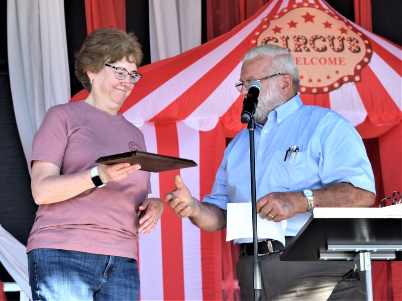Lifelong Killbuck resident and grand mrshal of the Early American Days parade Lisa Kauffman accepts a plaque commemorating her 44 years as an employee at the Killbuck Savings Bank from emcee Terry Logson at the Killbuck Early American Days Festival on Sunday.