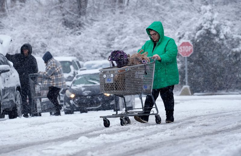 A woman makes her way to her car from the Kroger Blue Ash, Sunday, Feb. 16, 2025. What started as rain in the early morning hours, quickly changed to snow.
