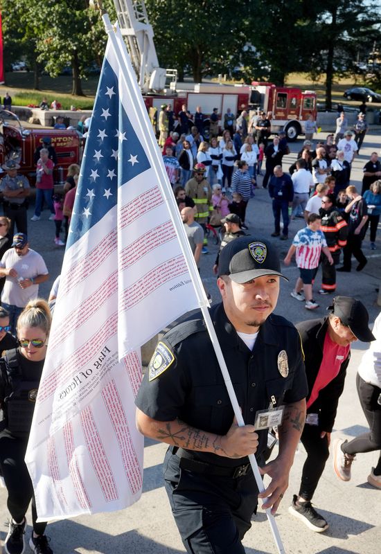 Officer Teo Romero of Summa Health Protective Services carries a flag with the names of all the victims of the Sept. 11, 2001, terrorist attacks during the annual 9/11 Memorial Stair Climb at the McKinley National Memorial, hosted by the Canton Fire Department.