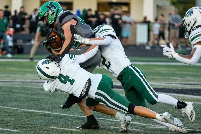 Ryan Slisz (4) of the Aurora Greenmen and Carter Romanack (2) of the Aurora Greenmen attempt to take down Casey Myser (25) of the Highland Hornets on a runSept. 12, 2025, in Granger Township, Ohio.