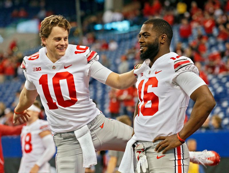 Ohio State Buckeyes quarterbacks Joe Burrow (10) and J.T. Barrett (16) warm up before the Big Ten Championship game against the Wisconsin Badgers at Lucas Oil Stadium in Indianapolis on Saturday, December 2, 2017.