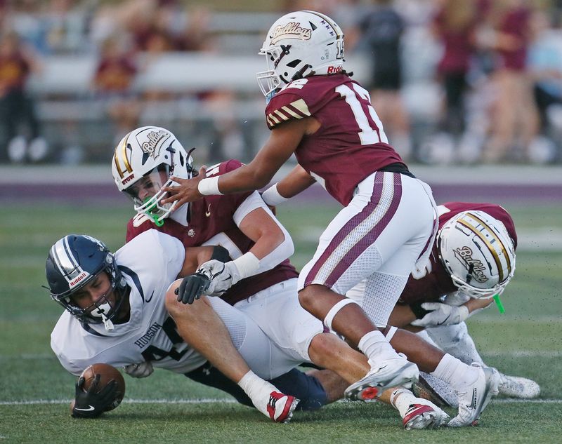 Hudson running back Reno Ferri is tackled by three Stow defenders in the first half, Sept. 19, 2025.
