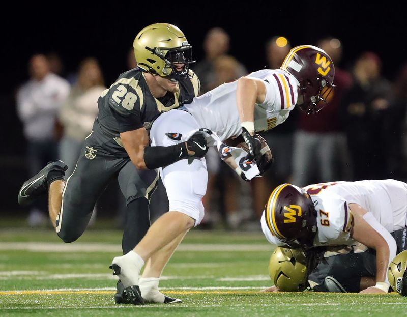 Archbishop Hoban linebacker Brydon Feister (28) wraps up Walsh Jesuit running back Marty Tobin (5) during the first half of a high school football game, Sept. 26, 2025, in Akron, Ohio.