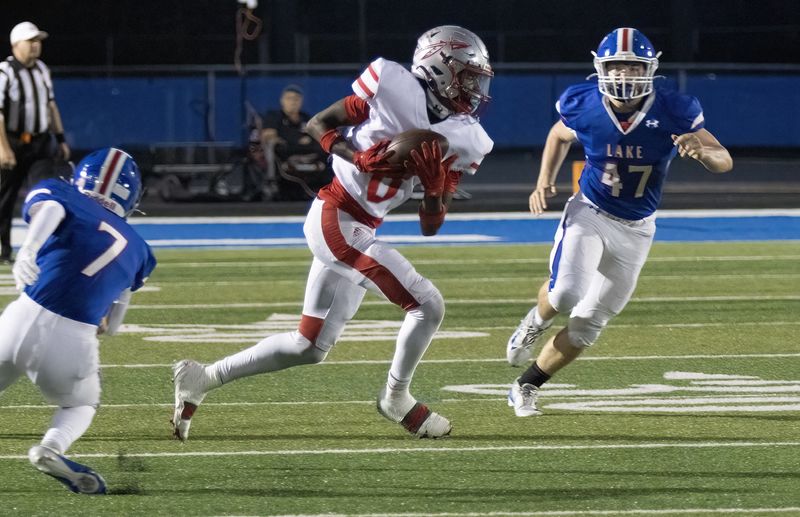 Ty Lipkins takes a pass reception to the 15-yard line and a first down between Lake’s Callen Pierce (7) and Kyle Hammer on Friday, Sept. 26, 2025.