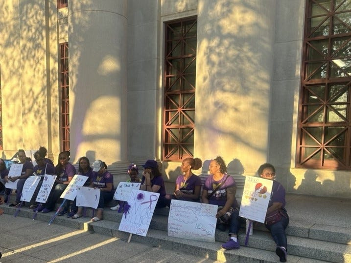 Supporters of domestic violence victims and survivors hold signs at a domestic violence awareness vigil on Oct. 1, 2025 outside of Columbus City Hall.