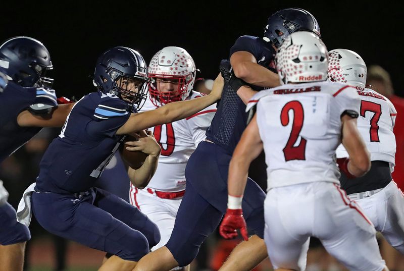 Hudson quarterback back Hayden Lipinski (18) picks up a block from his lineman as he runs for a short gain during the first half of a high school football game against Wadsworth, Oct. 3, 2025, in Hudson, Ohio.