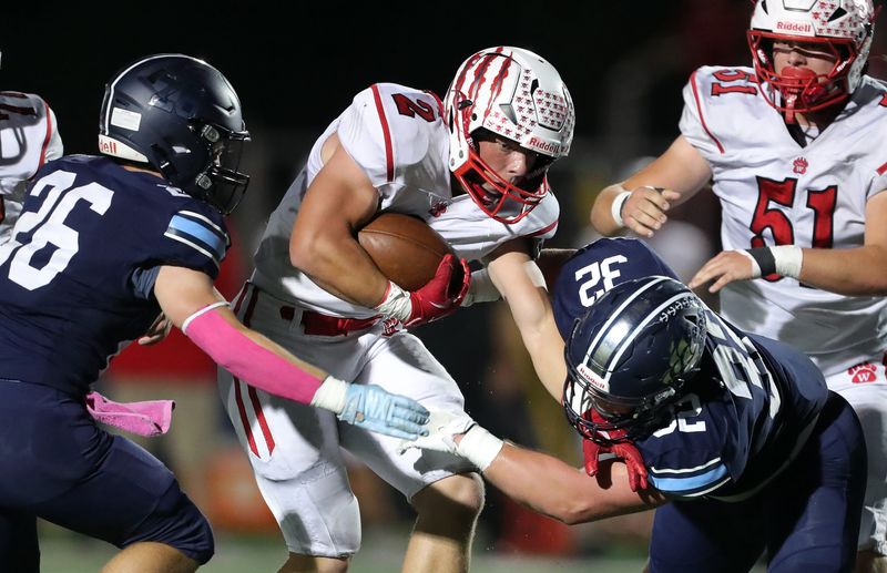 Wadsworth running back Gavin Madigan (2) picks up yards between Hudson linebacker Brennan Funyak (26) and linebacker Joseph Cavalcanti (32) during the first half of a high school football game, Oct. 3, 2025, in Hudson, Ohio.