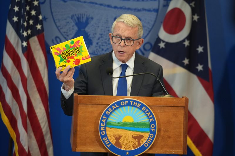 Ohio Gov. Mike DeWine holds a box of Gushers-style intoxicating candies as he announces a ban on the sale of intoxicating hemp products, such as THC-infused gummies and beverages sold in gas stations, tap rooms and retail shops, for 90 days. Intoxicating hemp products are any THC-containing items sold outside of licensed marijuana dispensaries. He announced the ban during a news conference at the Riffe Center in Columbus on October 8, 2025.