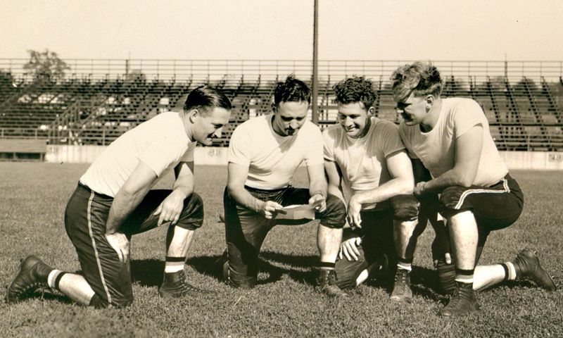 Massillon Tigers coaches, from left, Elwood Kammer, William Houghton, Bob Shertzer, Augie Morningstar look over a play in this 1941 photograph that is part of the Massillon Museum’s collection.