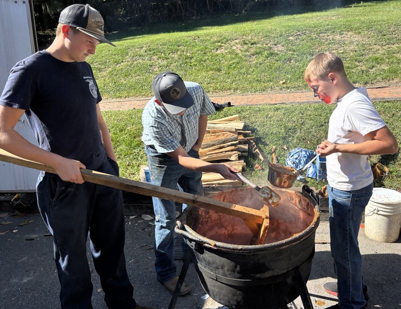 Jaxon Huff and Cater Osborne stir the apple butter while Wyatt Wilkin scoops it out to be jarred at the Apple Butter Stirrin' Festival in Roscoe Village.