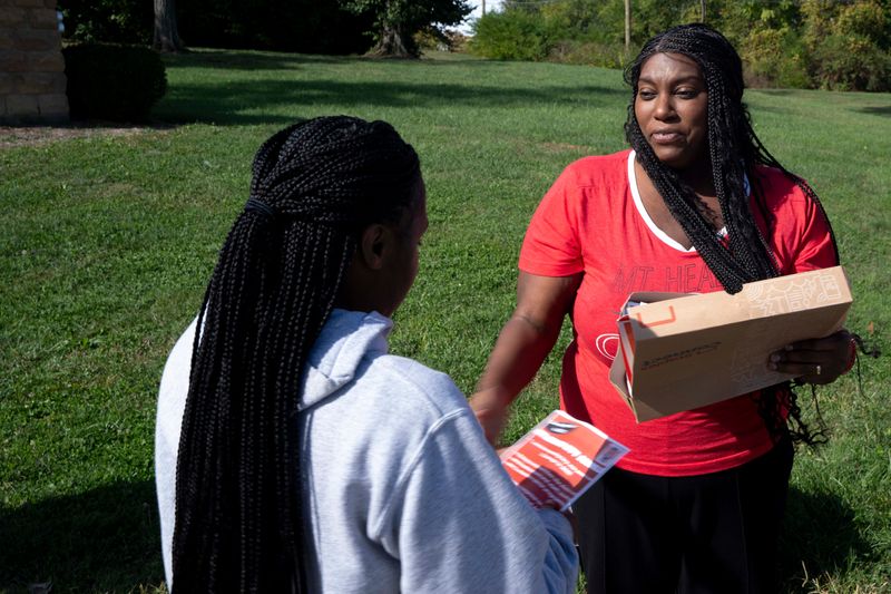 Diana Irving hands out pamphlets in support of a levy for Mt. Healthy schools outside Mt. Healthy High School in Mt. Healthy on Oct. 17, 2025.