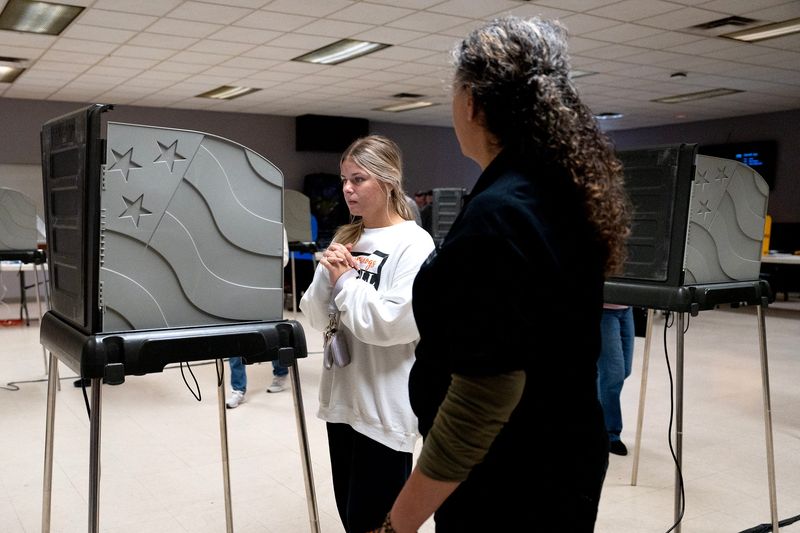 Assistant Voting Location Manager, Gina Dow helps first time voter, Megan Devito cast her ballot on Election Day at the American Legion in Newark, Ohio, Nov 4, 2025.