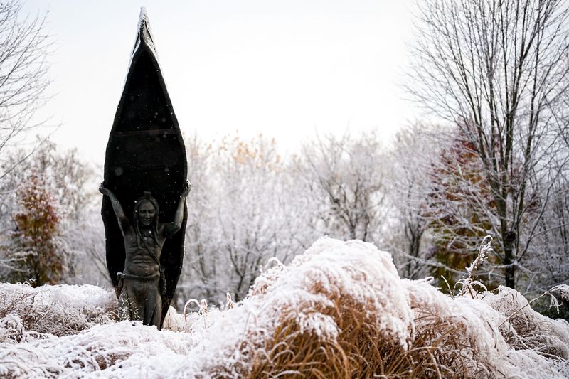 The first snowfall of the season around the Native American Carrying a Canoe sculpture in Akron, Ohio, Nov. 10, 2025.
