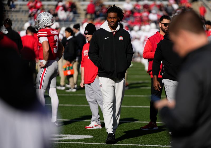Ohio State Buckeyes wide receiver Jeremiah Smith wears street clothes on the field prior to the NCAA football game at Ohio Stadium in Columbus on Nov. 22, 2025. Smith, along with fellow wide receiver Carnell Tate, did not play in the game.