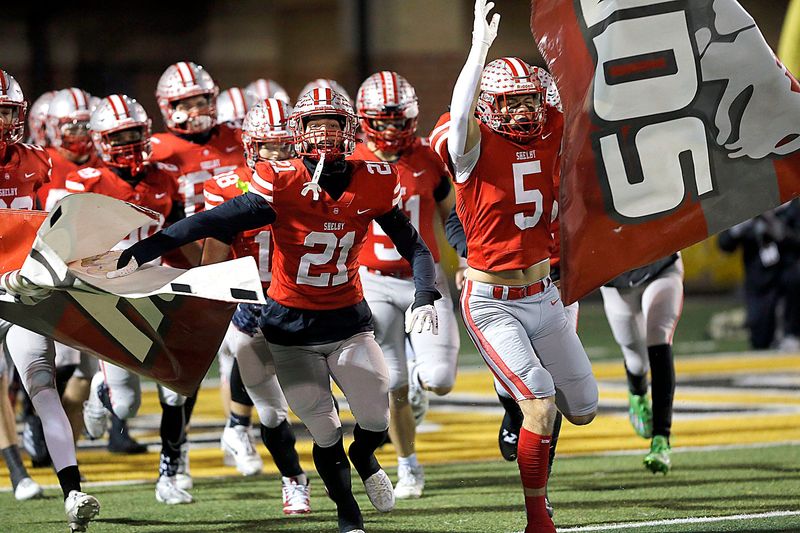 Shelby High School's Travis Slone (21) and Shelby High School's Sam Gwirtz (5) lead the team onto the field against Indian Hill High School during OHSAA Division IV State Semifinal high school football action Friday, Nov. 28, 2025 at Sidney High School. TOM E. PUSKAR/MANSFIELD NEWS JOURNAL