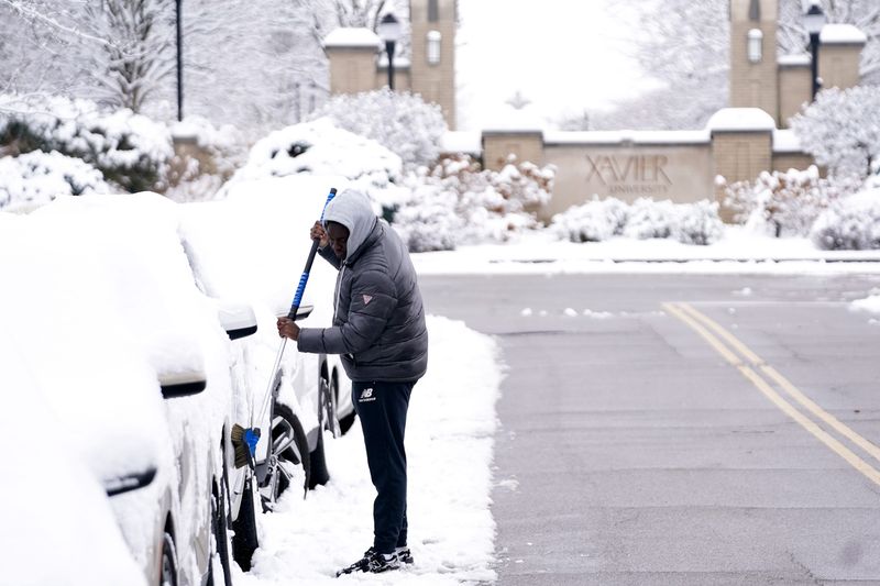 Adrian Reid, 21, clears snow off his car, Tuesday, Dec. 2, 2025, at Xavier University in Evanston.