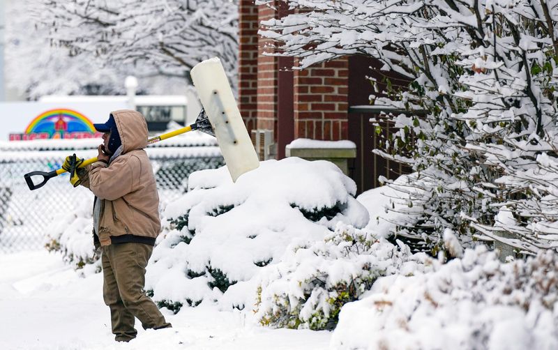 A man takes a break from shoveling snow from an apartment building on Vine Street in Carthage  on Dec. 2, 2025.