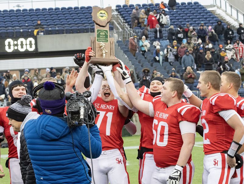 St.Henry’s Anderson Kramer (71) raises the Division VII State Championship trophy after defeating Hillsdale 37-3 on Dec. 6, 2025. Bob Rossiter / Special To The Canton Repository.