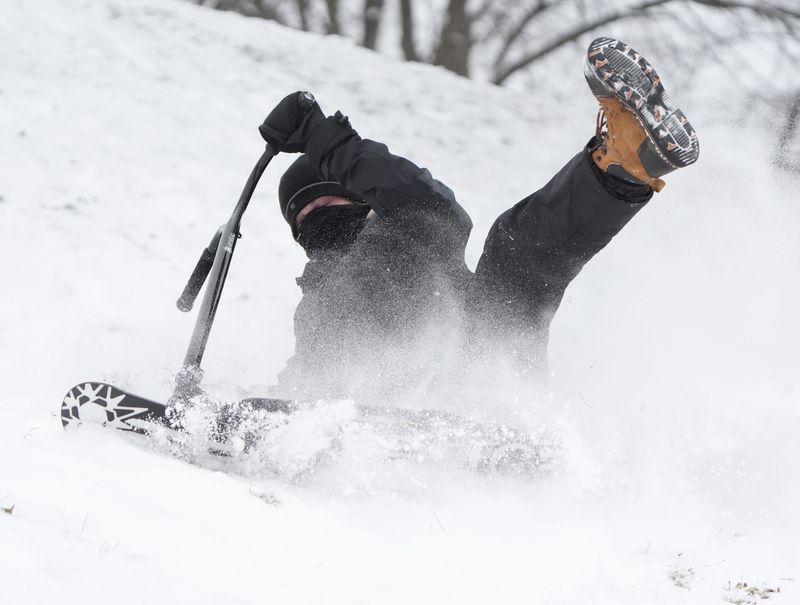 Jaden Mayo of Canton Township wipes out on his snow scooter at Monument Park in Canton Monday, Dec. 15, 2025.
