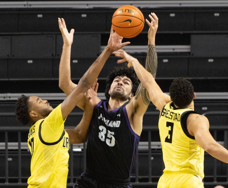 Oregon’s Kwame Evans Jr., left, and Jackson Shelstad battle Portland’s Cameron Williams, center, for a rebound during the second half at Matthew Knight Arena in Eugene Dec. 17, 2025.