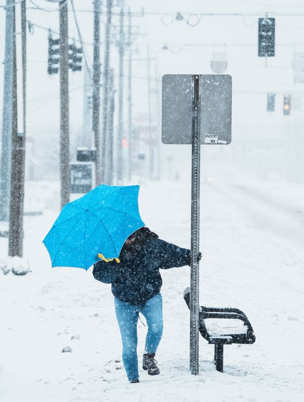 Rebecca Wise uses an umbrella to cut down on the blowing snow on her face as she heads home on State Street in New Albany, Indiana Monday morning as Winter Storm Blair moved through the metro Louisville area Jan. 6, 2025. Wise said she was injured after driving in ice years earlier and stopped driving.