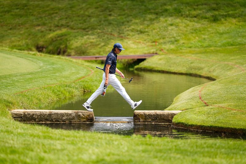 Rickie Fowler hops the creek to the 14th green during the first round of the Memorial Tournament at Muirfield Village Golf Club in Dublin on May 29, 2025.