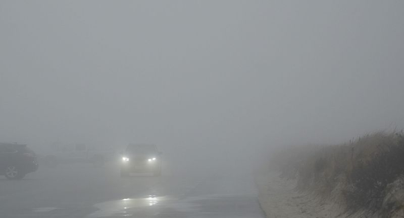 The headlights of a car breaks through the heavy afternoon fog at West Dennis Beach. 
Photo taken Dec. 29, 2025