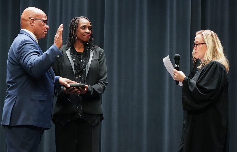 Returning Akron school board member Gregory Harrison puts his hand on the Bible held by Carla Chapman as Summit County Common Pleas Judge Jennifer Towell administers the oath of office in the auditorium of Garfield Community Learning Center in Akron on Jan. 5, 2026.