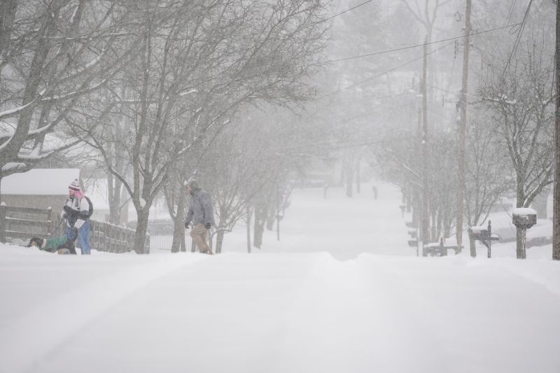 Pedestrians brave deep snow to walk their dog in the Mount Washington neighborhood of Cincinnati on Sunday, Jan. 25, 2026. The National Weather Service issued a winter storm warning until Monday at 6 p.m. for Hamilton County, Ohio.