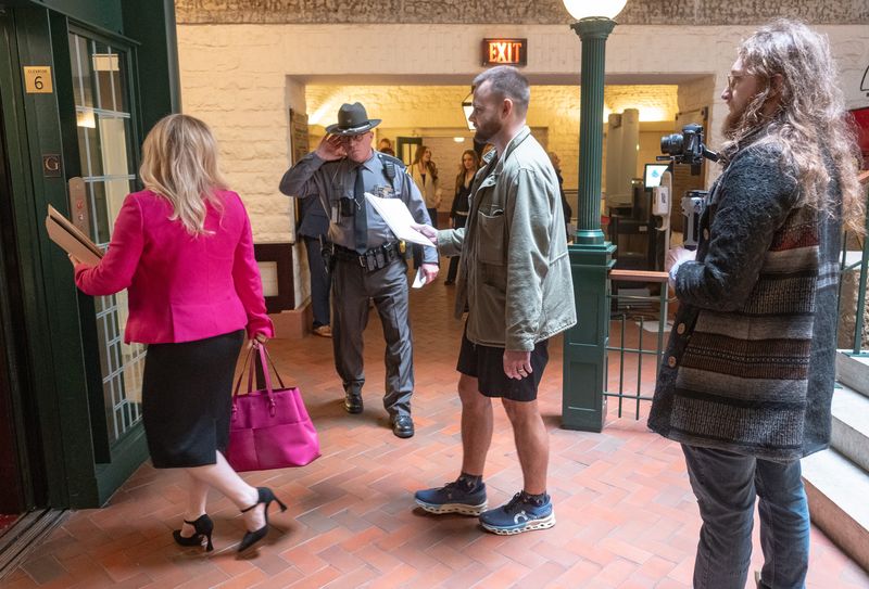 State representative Melanie Miller asks for help from a State Highway patrolman to avoid questions from D.J. Byrnes.