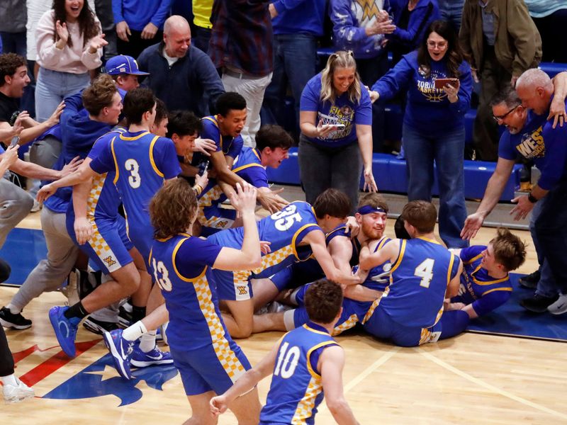 West M boys basketball players mob Noah Morrison after he hit the game-winning shot at the buzzer in a 59-57 win against St. Clairsville in a Division V regional semifinal on Wednesday, March 11, 2026, at Winland Memorial Gymnasium in Zanesville, Ohio. West reached its first Elite 8 since 1990.