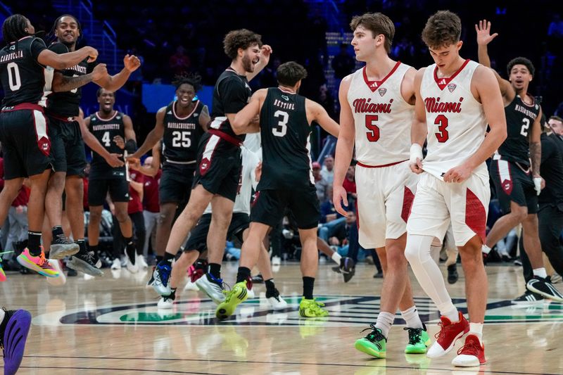 Miami RedHawks guard Peter Suder (5) and guard Luke Skaljac (3) leave the floor as UMass Minutemen forward Leonardo Bettiol (3) celebrates a win after the final buzzer of the second half of Mid-American Conference Tournament first round game between the Miami RedHawks and the UMass Minutemen at Rocket Arena in Cleveland on Thursday, March 12, 2026. Top-seeded Miami was eliminated from the tournament with an 87-82 loss to the Minutemen.
