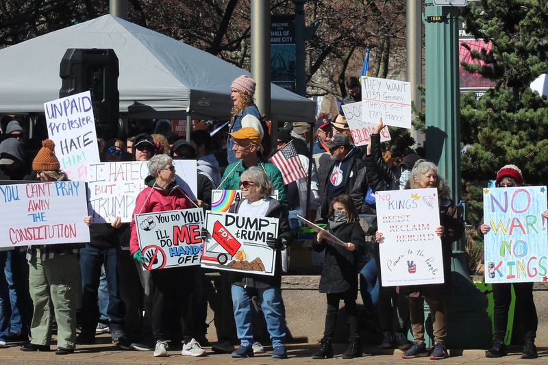 Protesters hold signs at the No Kings rally in downtown Canton on March 28.