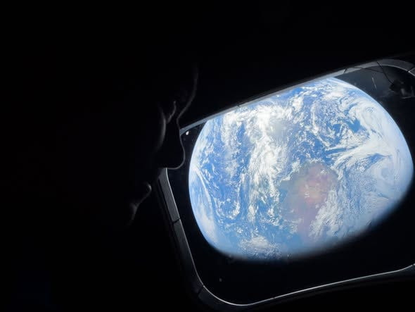 Artemis II commander Reid Wiseman gazes out at Earth through a window of the Orion spacecraft in April 2026.