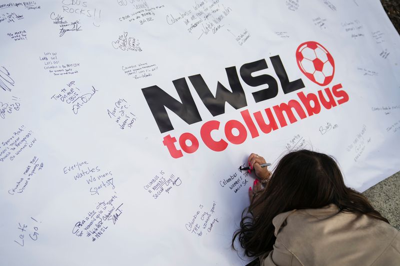 Prior to a Columbus City Council hearing about public funding for a women's professional soccer team, Sol Tsonis signs a banner for the NWSL to Columbus movement as supporters rally outside Columbus City Hall on April 6, 2026.