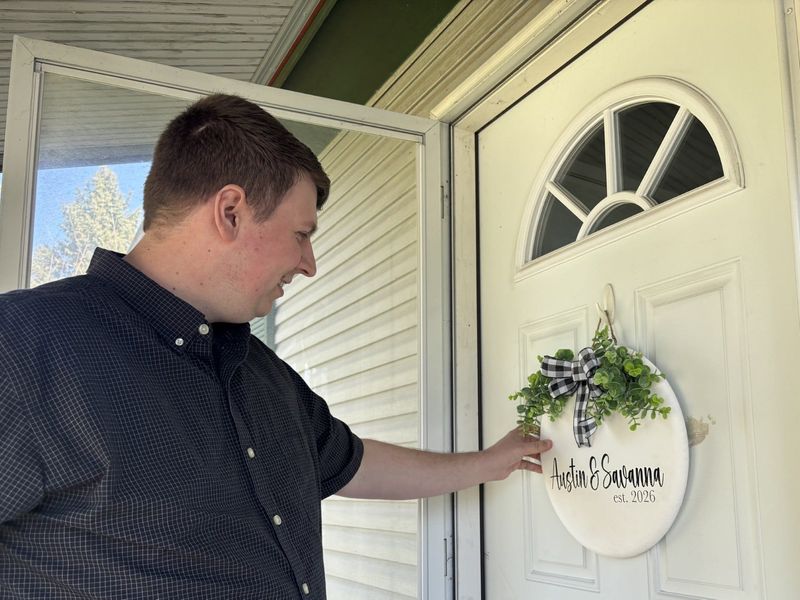 Austin Spillman, 27, hangs a sign on the door of his new home in Southeast Columbus he bought with fiancé Savanna Wooten, 25, in March.