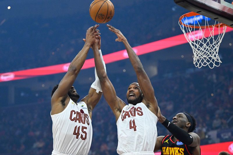 Cleveland Cavaliers guard Donovan Mitchell (45) and center Evan Mobley (4) reach for the ball as Atlanta Hawks forward Onyeka Okongwu looks on April 8, 2026, in Cleveland.