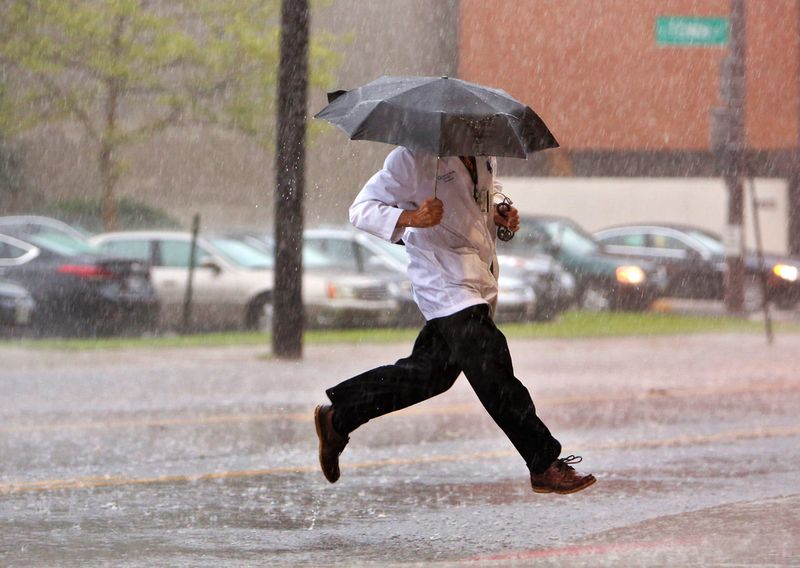 Dr. Bob Skully of Columbus makes a dash across Grant St. during a afternoon thunderstorm in Columbus as he shows up for work at Grant Medical Center July 14, 2015.