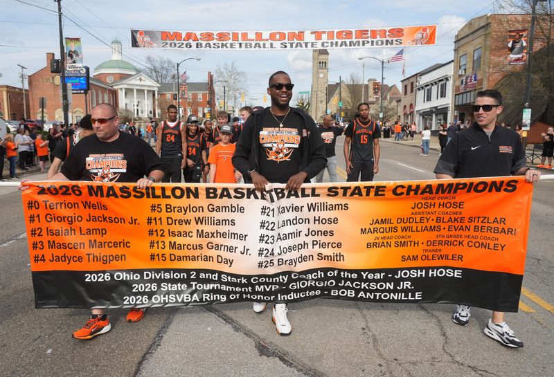 The Massillon Tiger boys' basketball team marches down Lincoln Way on April 12 during a parade to celebrate the squad's first state championship. Leading the way are assistant coaches Brian Smith, left, Jamil Dudley and Evan Berbari.