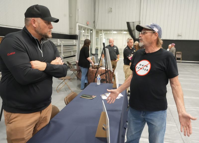 William A. Dazey, right, of Perry Township asks questions of Ben Smith with Clayco Construction at an informational meeting on data centers held April 15 at Perry High School.