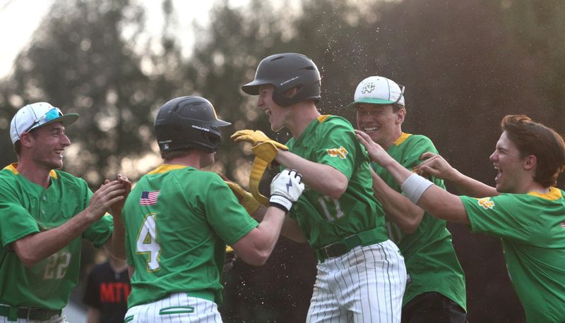 Newark Catholic players swarm Alex Nagel after his game-winning hit gave the Green Wave a 4-3 eight-inning victory against visiting Mount Vernon on April 15, 2026.