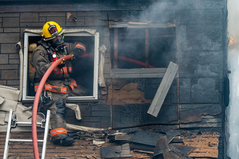 An Akron firefighter pulls a hose line into the second story of a home during a residential structure fire that burned two houses in the 100 block of East Voris St, April 16, 2026, in Akron, Ohio.