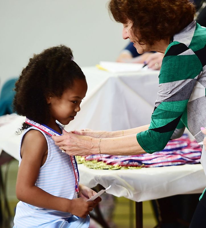 Alliance Early Learning School student Liliana Eilam receives a medal April 18, 2026, from Alliance Quota Club president Kim Anthony during the 2026 Sparkles Awards ceremony at Alliance Commons.