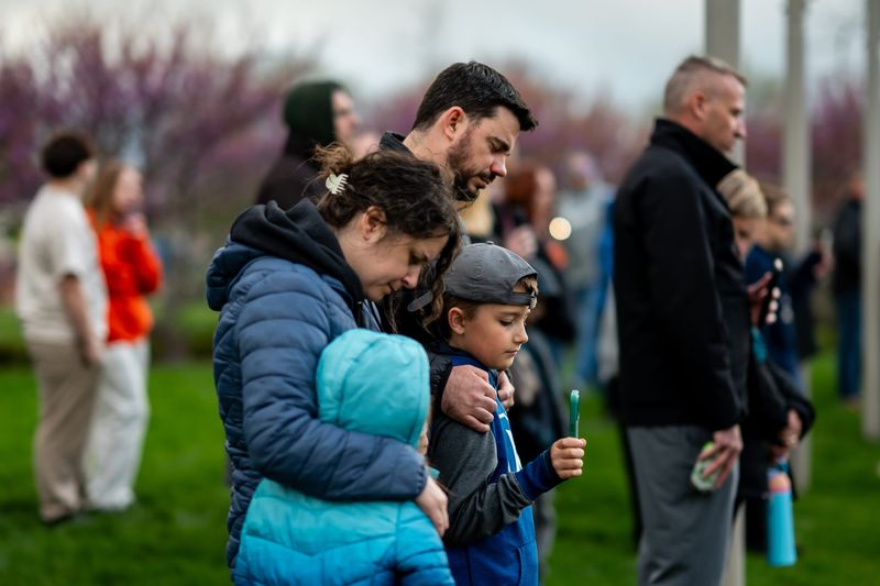 A family participates in a candlelight vigil held to honor the life of Sam Rife, April 19, 2026, at Green Central Park Amphitheater in Green, Ohio.