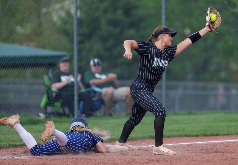 Tallmadge baserunner Brynlee Schwartz, bottom, dives safely back to third under Aurora third baseman Lila Bultrowicz during the sixth inning of a high school softball game, April 22, 2026, in Aurora, Ohio.