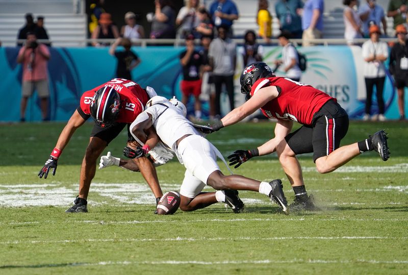 Dec 23, 2025; Boca Raton, FL, USA; Toledo Rockets safety Emmanuel McNeil-Warren (7) forces a fumble against Louisville Cardinals wide receiver Antonio Meeks (15) during the second quarter of the Boca Raton Bowl at Flagler CU Stadium. Mandatory Credit: Jeff Romance-Imagn Images