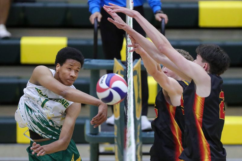 Firestone’s Elijah Myers, left, hits the ball into a pair of Brecksville players during the second set of a high school volleyball match, April 27, 2026, in Akron, Ohio.