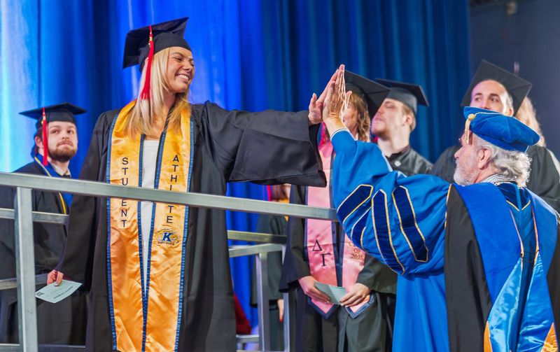 Kent State President Todd Diacon high-fives a student during the 2025 fall commencement.