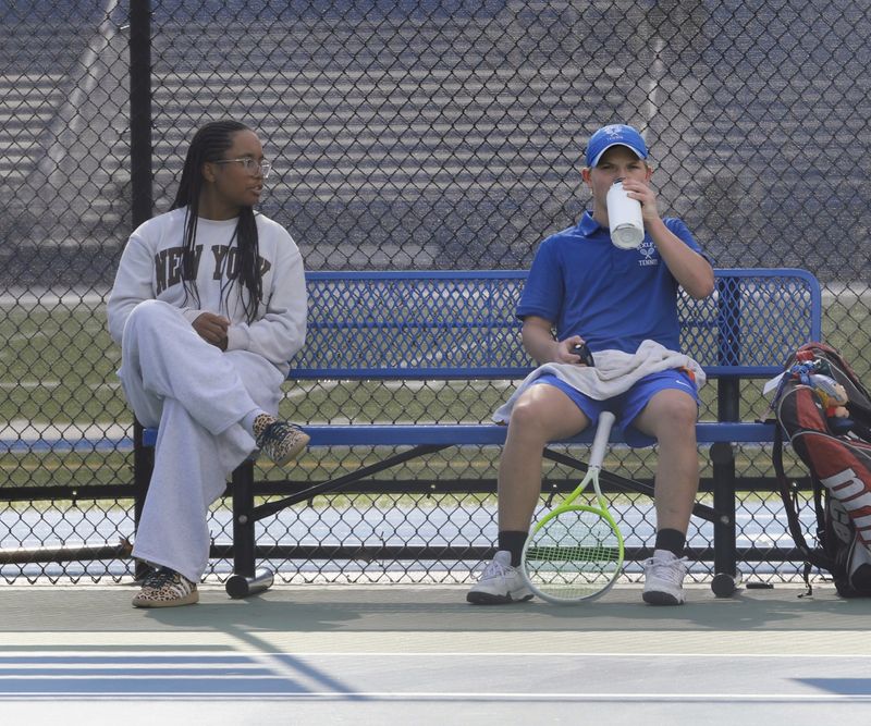 Bexley's Amiya Bowles, left, chats with freshman singles player Harrison Lessard during his April 29 match against New Albany's Tyler Thomas. Bowles was sidelined by a wrist injury that day but plans to play singles in the Division II postseason.