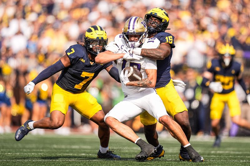 Michigan linebacker Ernest Hausmann (15), right, and defensive back TJ Metcalf (7) tackles Washington wide receiver Denzel Boston (12) during the second half at Michigan Stadium in Ann Arbor on Saturday, Oct. 18, 2025.